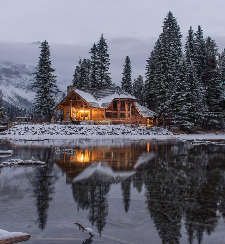 wooden house near the pond with snow