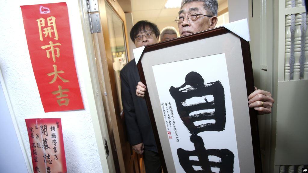 台北铜锣湾书店创办人林荣基手持台湾公民参与协会理事长何宗勋写的“自由”字画。