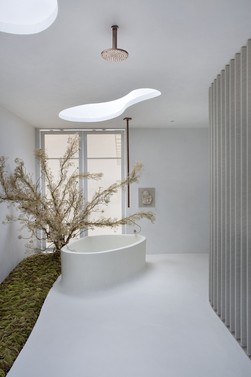 Banheiro com paredes e teto brancos, banheira de imersão branca e canteiro com gramado.