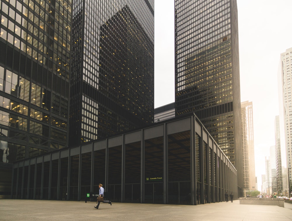 A man with a leather suitcase running near an office building