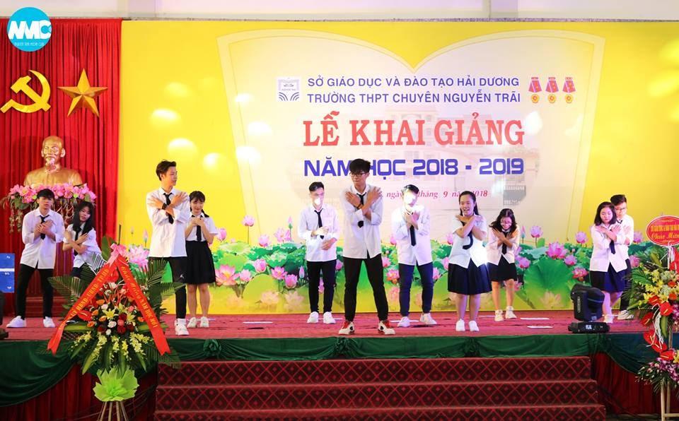 Image may contain: 3 people, people smiling, people on stage, people standing and indoor