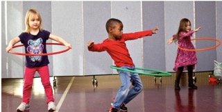 Three children, two girls and one boy playing with a hula hoop