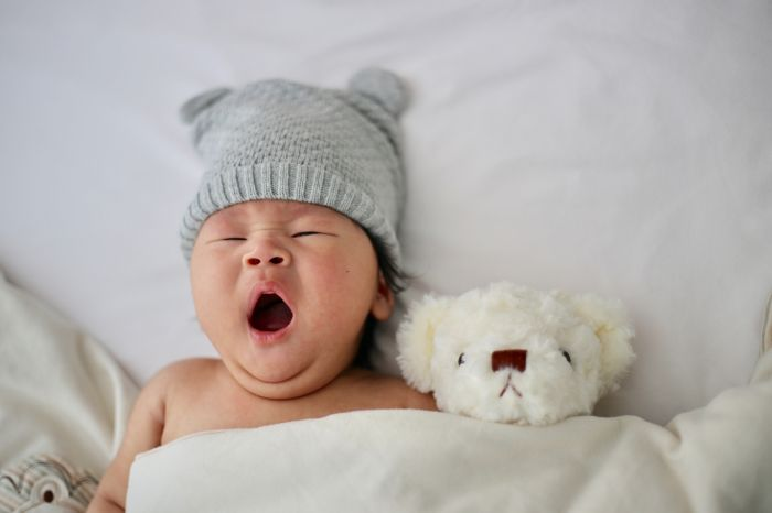 a baby yawning sleeping besides his toy