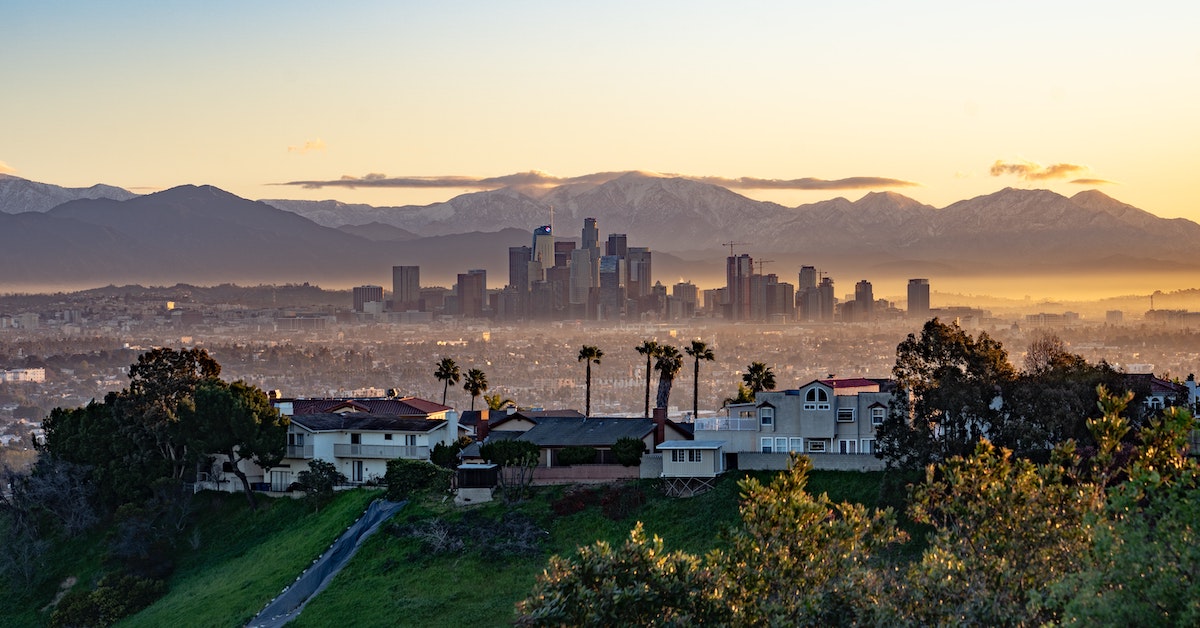 A golden hour view of the Hollywood hills, downtown skyline, and mountain range among a smoggy Los Angeles.