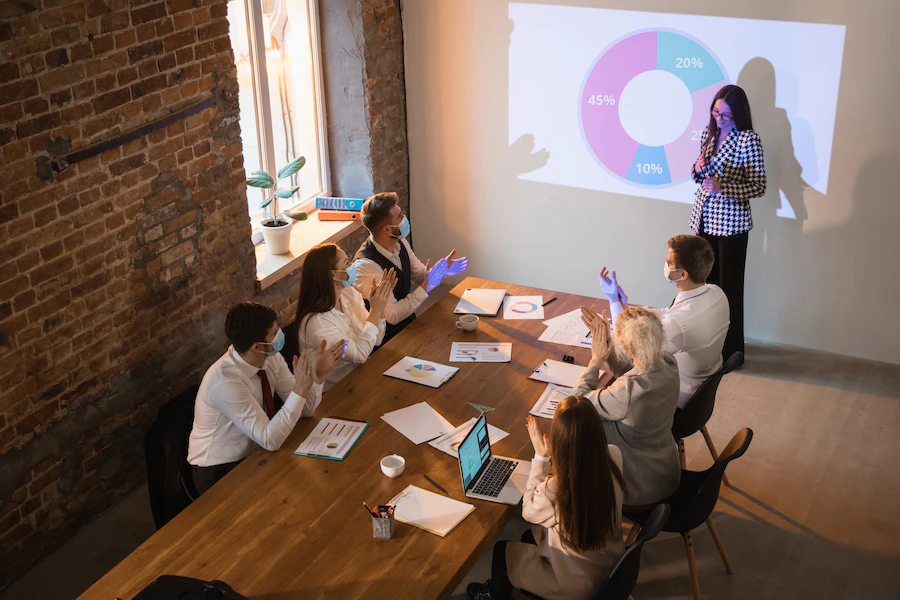 O que não pode faltar em um pitch: mulher apresentando slide com um gráfico durante uma reunião